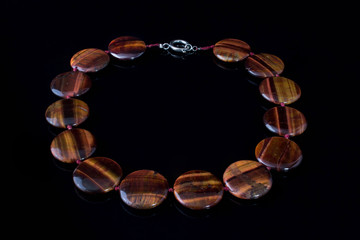 Beautiful, elegant necklace made of stone tiger eye on a black background