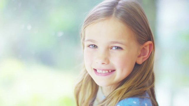  Portrait of pretty smiling little girl sitting by a window.