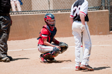 Youth baseball catcher looking for signals from coach.