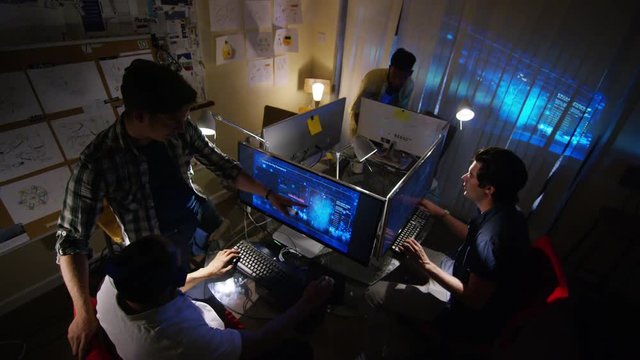  Young creative computer design team working together in dark office.