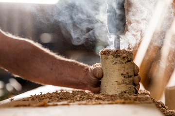 woodworker holding and drilling a log