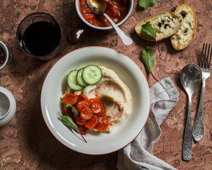 Healthy vegetarian lunch - bean puree with tomato sauce, homemade bread and a glass of red wine on a stone background. Top view