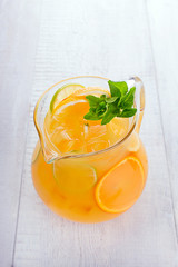 Jug of lemonade on a white wooden background