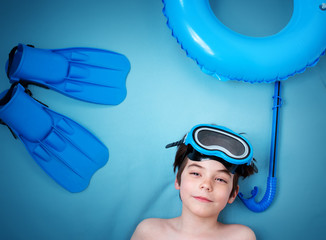 Child lying on blue blanket with swimming mask and flippers