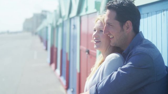  Portrait of romantic lovers standing in front of colourful beach huts