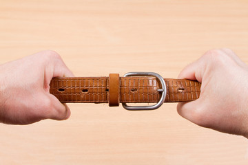 Two hands pulling a leather belt