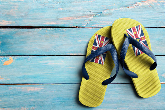 Thongs with flag of Niue, on blue wooden boards