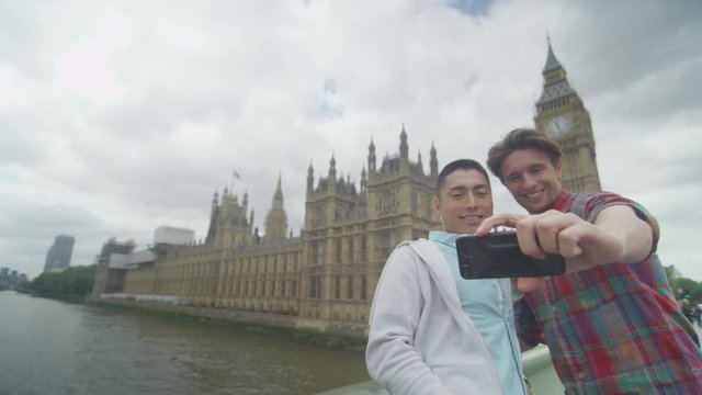  Male friends pose to take a selfie in front of London Houses of Parliament