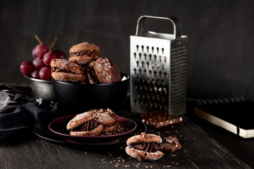 Maroni cookies and grapes on dark wooden background