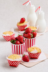 Delicious muffins, strawberries and milk in bottles.