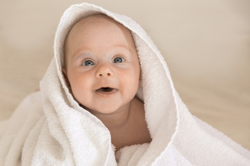 Cute baby girl smiling. Covered with a white towel