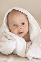 Cute baby girl smiling. Covered with a white towel