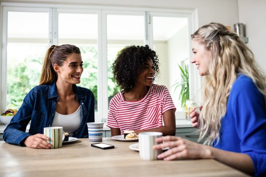 Female friends smiling while having breakfast at table