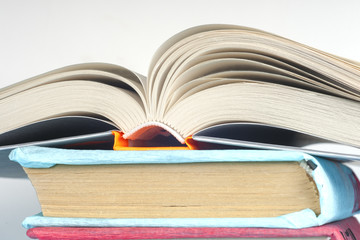 Open book, stack of colorful hardback books on light table. Back to school. Copy space for text
