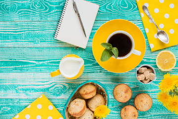 cup of black tea on yellow plate and yellow milk jug cane sugar, notebook, pen, cakes, dandelions,...