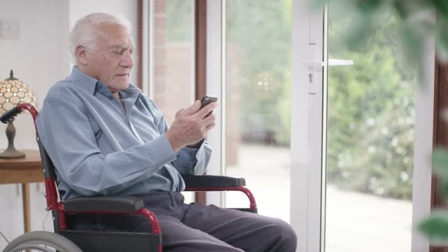  Elderly man in a wheelchair talking on mobile phone 