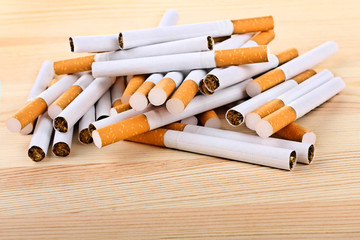 a bunch of cigarettes with orange filters on a wooden table