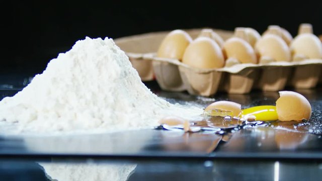  Fresh egg in the shell dropping and breaking beside a heap of flour
