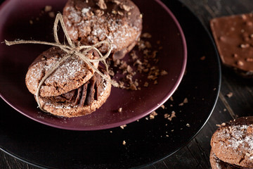 Organic cookies with pieces of chocolate on the dark plate and o