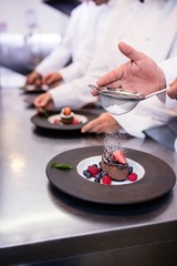 Fototapeta na wymiar Close-up of chef finishing a dessert plate