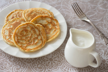 Freshly baked pancakes with sour cream on a textile tablecloths
