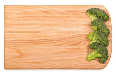 Wooden cutting board with pieces fresh broccoli isolated on white.