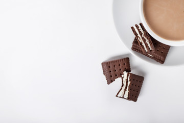 Biscuits on white plate and cup of coffee, top view