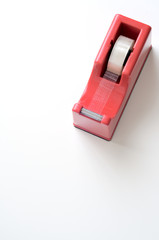 Porta nastro adesivo rosso su scrivania bianca, sfondo verticale