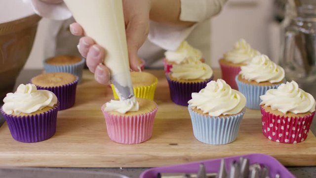  Woman with home bakery business piping cream onto cupcakes