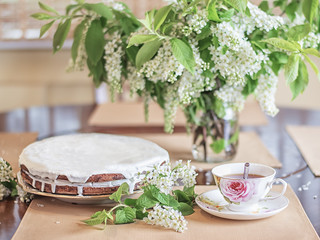 homemade Cake with a cup of tea and cherry flowers on the wooden