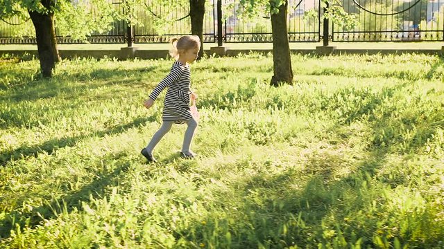 Little girl running in the park. It accelerates urban pigeons, for her fun. 