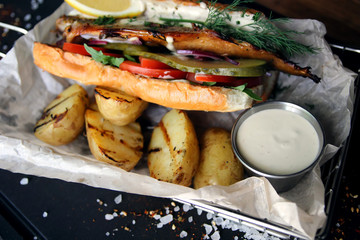 Baked potatoes, hamburger with fish and vegetables and sauce..