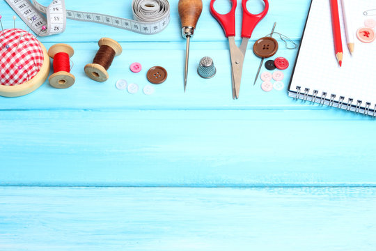 tools tailor spools threads buttons needle sewing  blue wooden background
