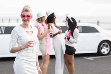 Frivolous women drinking champagne next to a limousine