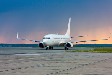 Fototapeta na wymiar Taxiing aircraft early in the morning on the main taxiway to the background of the rain