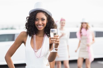 Happy friends drinking champagne in front of a limousine - obrazy, fototapety, plakaty