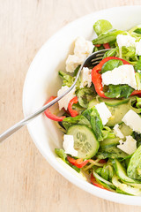 Frisch zubereiteter gemischter Salat mit Fettkäse in einem weißen Teller.