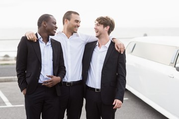 Handsome men posing next to a limousine