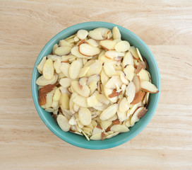 Top view of a bowl filled with sliced almonds on a wood table top