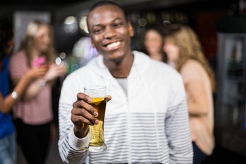 Smiling man showing a beer with his friends