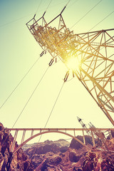 Vintage toned electricity transmission tower against sun.