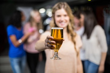 Smiling girl showing a beer with her friends