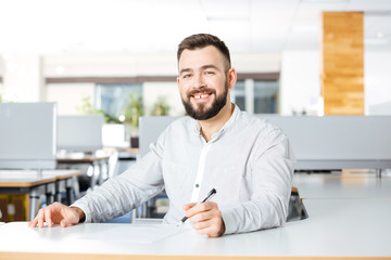 Cheerful businessman working and writing in office