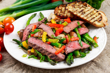 Grilled steak with stir-fried vegetables on plate.