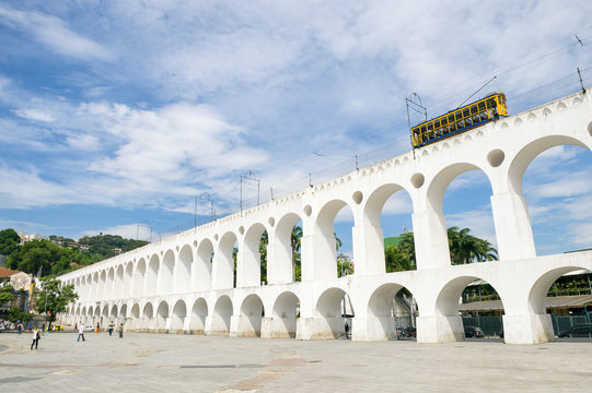 Bonde de Santa Teresa tram train drives along distinctive white arches of the landmark Arcos da Lapa in Centro of Rio de Janeiro Brazil