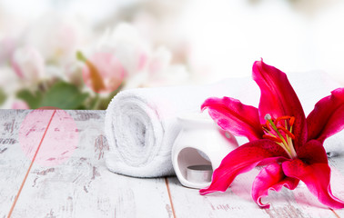 spa massage setting with lilium, oil, towel and salt on wooden background