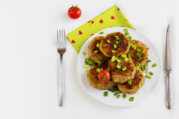 Roasted chicken cutlets with green onion on white plate and small cherry tomatoes on white table. Top view.