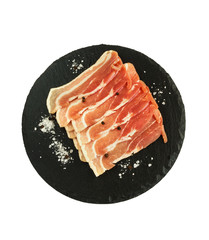 Raw sliced bacon on black stone. Isolated on white background. Top view.