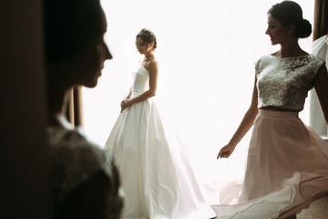 Naklejka premium Sensual bride next to the window with her friends