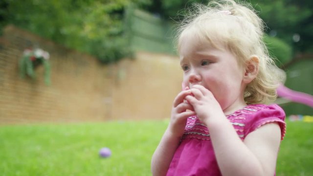  Portrait of little girl with pacifier & soft toy sitting in the garden